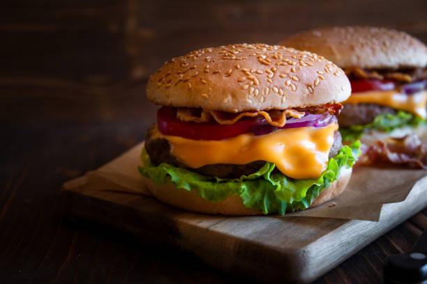 istock Burger with cheese, bacon, tomato and lettuce on dark wooden background 1273825133