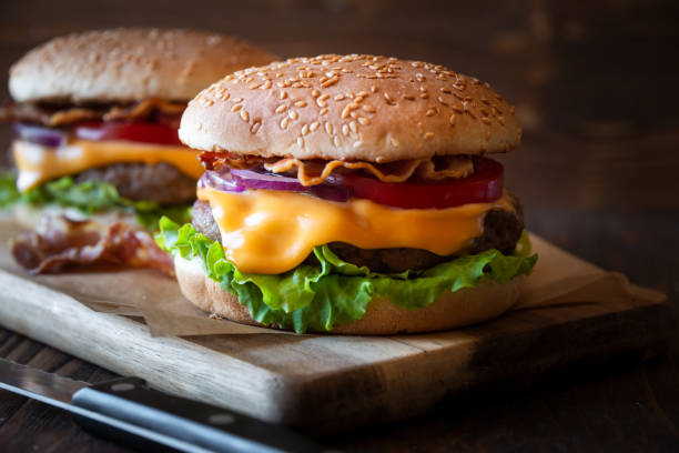 istock Burger with cheese, bacon, tomato and lettuce on dark wooden background 1273825727