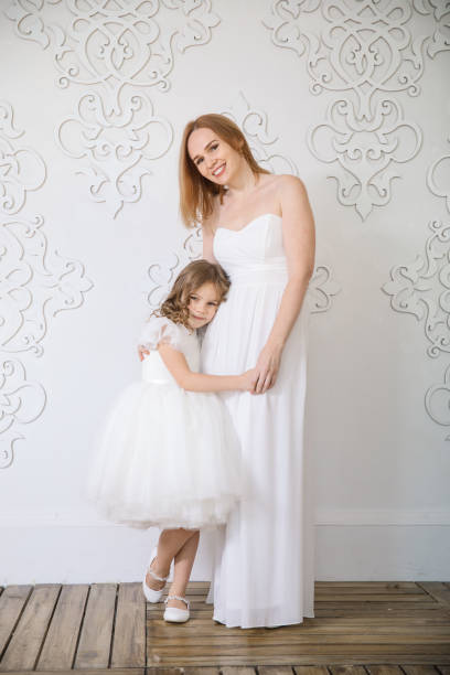 istock mother and daughter in white evening dresses. 1273826315