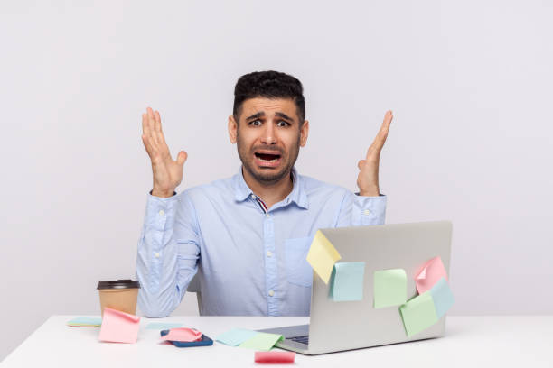 istock Overtime, overwork concept. Shocked scared man employee sitting in office workplace, raising hands screaming 1273827675