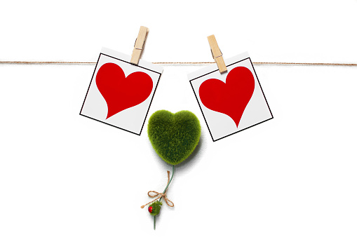 Red hearts with sheet of photo papers hanging on the clothesline isolated