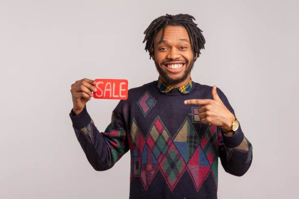 extremely excited african man with dreadlocks and beard pointing finger on sale sign in his hand with toothy smile on face, discount - men african descent giving flower imagens e fotografias de stock