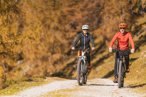 couple on a bike ride through autumn colored rural landscape - logging road imagens e fotografias de stock