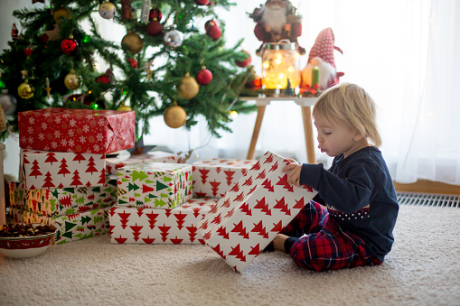Happy child, boy, opening presents on christmas day, dressed in pajamas