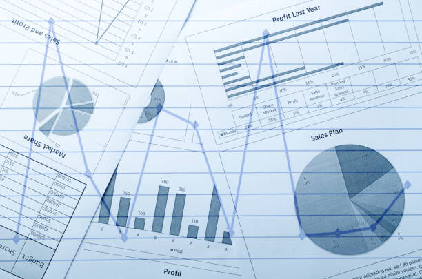 Vertical image.Stack of silver coins and business documents, graphs of profit