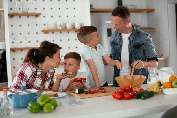 istock Mother and father making breakfast with sons. 1273833336