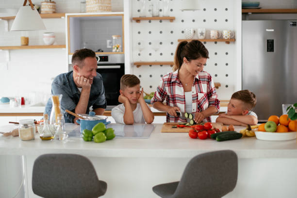 istock Mother and father making breakfast with sons. 1273833669