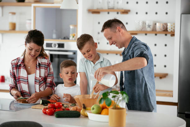 istock Mother and father making breakfast with sons. 1273833800