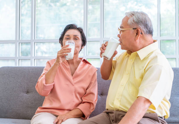 istock Two senior couple is drinking milk while relaxing on a sofa living room for retiredment wellness and healthy lifestyle concept. 1273834827