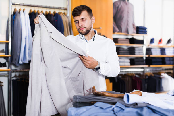 istock Positive guy customer choosing new jacket in shop 1273835375
