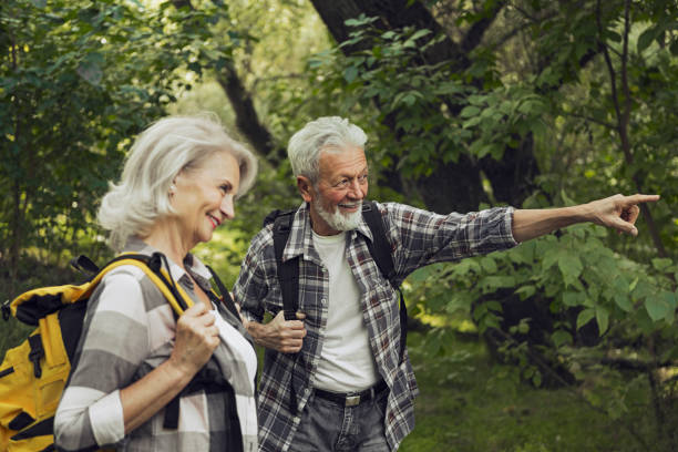 istock Senior couple hiking through the forest and exploring nature pointing a way 1273836132
