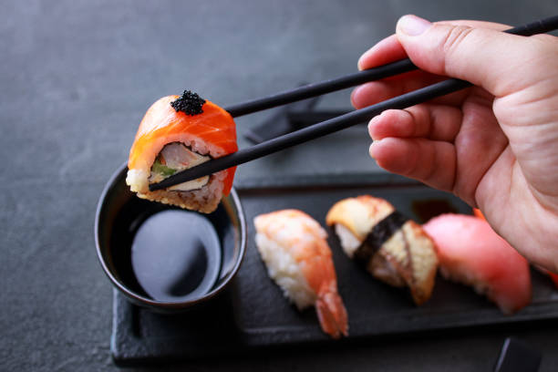 istock Eating sushi. Hand taking sushi roll from plate 1273837662