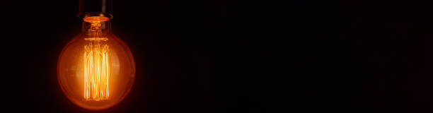 istock Vintage light bulb on a black background, long banner. Glowing edison bulb 1273838088