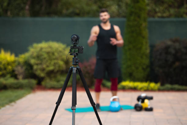 istock Male athlete doing exercise in backyard and filming vlog. 1273839556