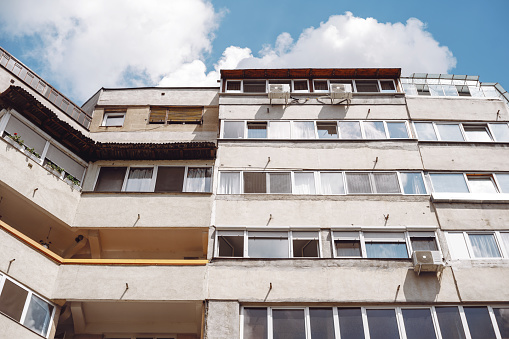 Oradea, Romania - May 28, 2018: A low angle view of an old communist apartment building with air conditioners against the cloudy sky.