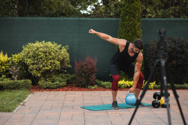 istock Male athlete doing exercise in backyard and filming vlog. 1273841332