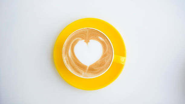 istock hot latte art in yellow cup on working desk 1273841423
