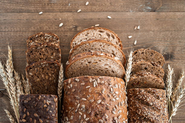 istock Different loaves of whole grain bread from the bakery are cut into pieces. Composition with seeds, sesame seeds and wheat ears. Top view. 1273841642