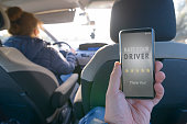 Passenger using smart phone app to rate a taxi or modern peer to peer ridesharing driver