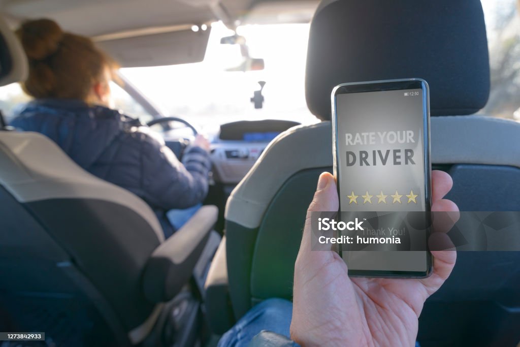 Passenger using smart phone app to rate a taxi or modern peer to peer ridesharing driver Passenger is sitting on the back seat of the car and using smart phone app to rate a driver. Taxi or modern peer to peer ridesharing concept Crowdsourced Taxi Stock Photo