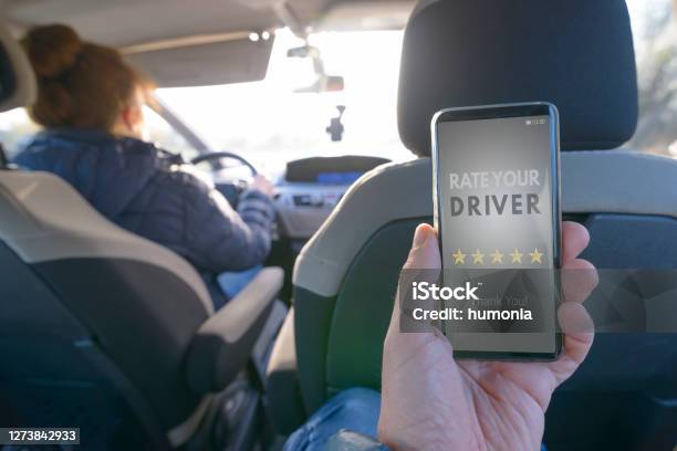 Passenger Using Smart Phone App To Rate A Taxi Or Modern Peer To Peer Ridesharing Driver Stock Photo - Download Image Now