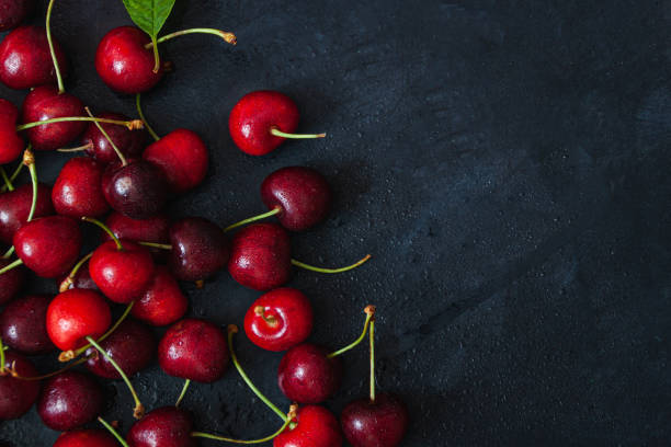 Cherry with leaf on plate and water dropsand on grey stone table