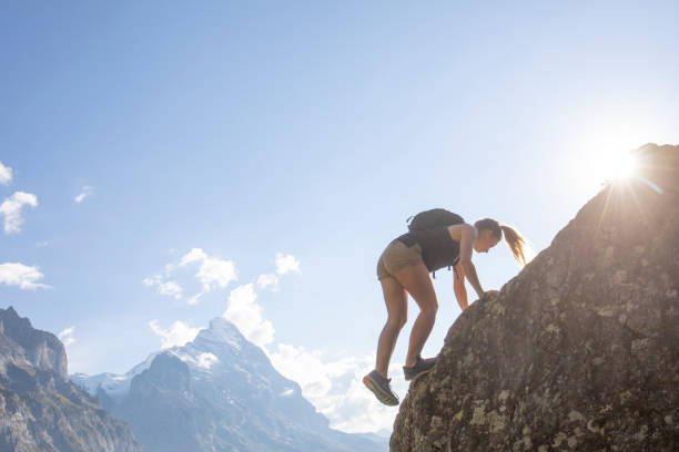istock Young woman scrambles up mountain ridge at sunrise 1273844708