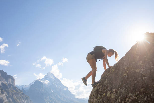 istock Young woman scrambles up mountain ridge at sunrise 1273845255