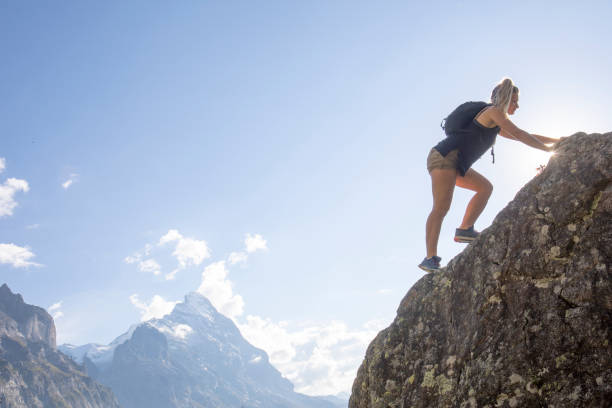 istock Young woman scrambles up mountain ridge at sunrise 1273845291