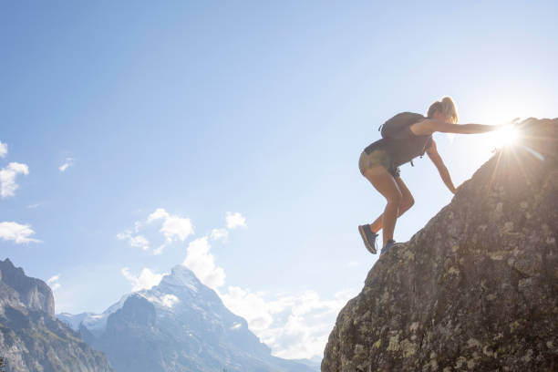 istock Young woman scrambles up mountain ridge at sunrise 1273845306