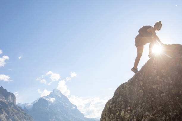 istock Young woman scrambles up mountain ridge at sunrise 1273845317