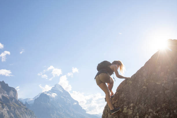 istock Young woman scrambles up mountain ridge at sunrise 1273845348