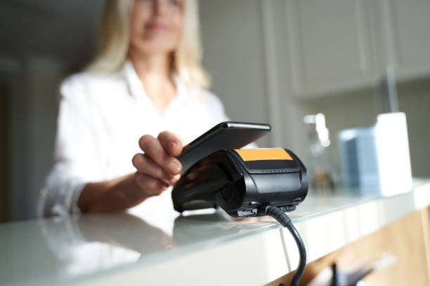 hermosa señora sosteniendo su teléfono inteligente cerca del lector de tarjetas de crédito - human skin sparse washing face human face fotografías e imágenes de stock