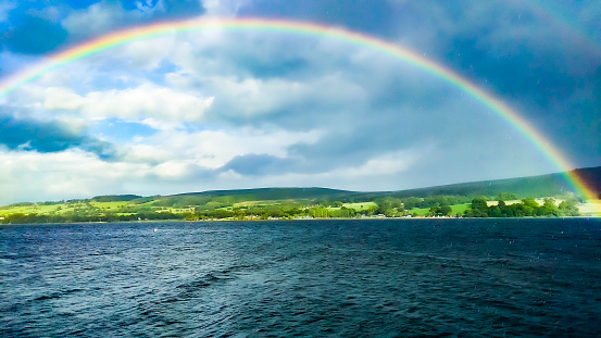 Rainbow by the lake at a cloudy sky