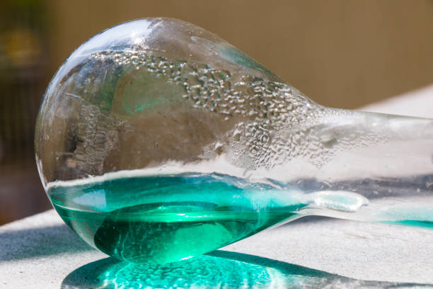 istock Laboratory glassware with green color reagents, sunlight and shadows. 1273847000