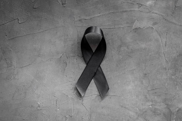 istock Black awareness ribbon on dark background. Mourning symbol 1273848810
