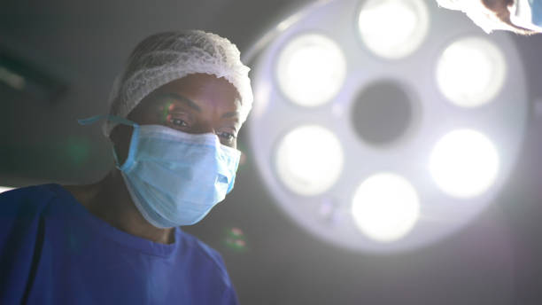 수술실에서 수술을 하는 여성 외과 의사 - 수술용 라이트 뉴스 사진 이미지