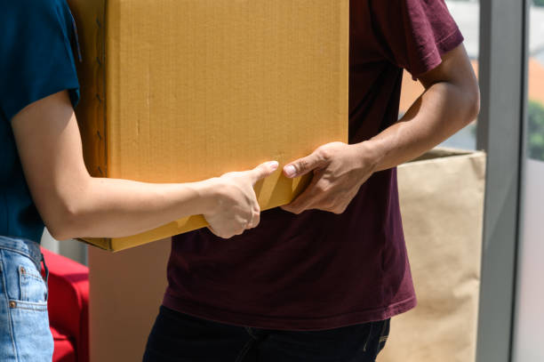 de cerca de la mano de la joven pareja asiática cuando llevan una gran caja de cartón mientras se reubican en un nuevo hogar en el día de mudanza, celebrando la mudanza al nuevo concepto de hogar - moving house physical activity real estate couple fotografías e imágenes de stock