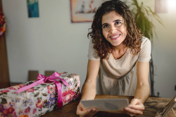 istock Smiling woman receive a gift box and write or read a greeting card. Give concept. 1273851128