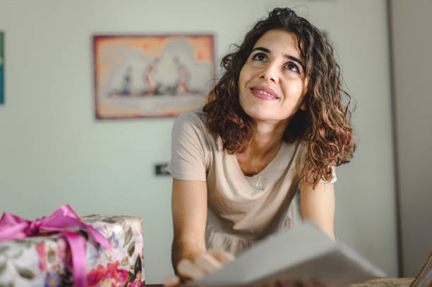istock Smiling woman receive a gift box and write or read a greeting card. Give concept. 1273851129