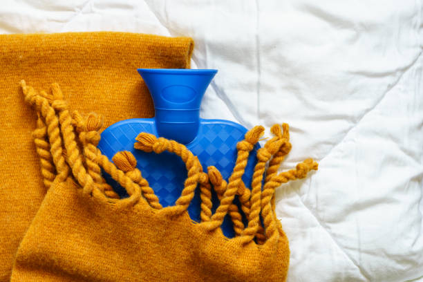 uma garrafa de água quente azul enrolada em um cobertor amarelo - hot water bottle - fotografias e filmes do acervo