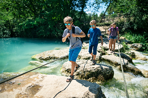 Mother and three kids hiking near river Elsa in Colle di Val d'Elsa, Tuscany. Family is crossing the river over the rock bridge.
Nikon D850