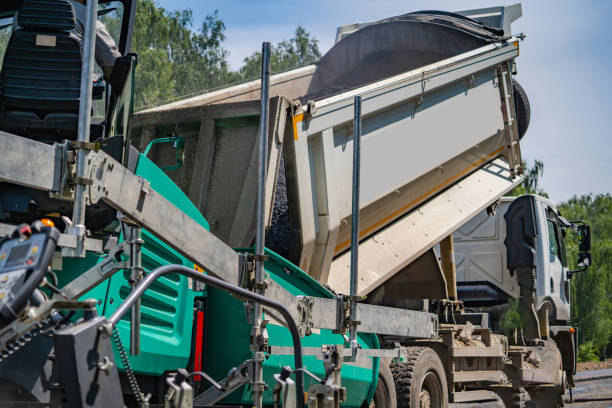 Flattering new asphalt at road. Selective focus on special machinery. Workers on blurred background.