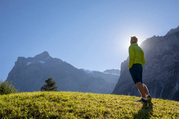 istock Man walks through grassy meadow at sunrise 1273853818