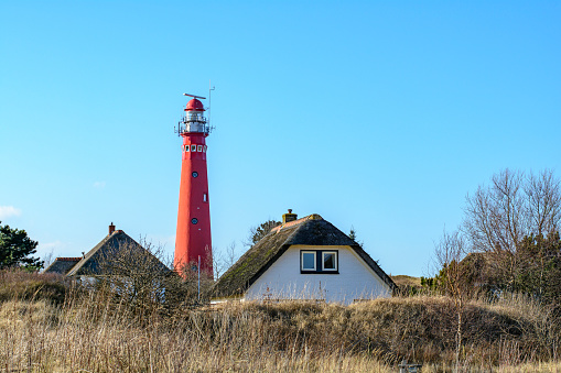 White lighthouse in the dunes in the small Dutch village of Egmond aan Zee in the Netherlands.