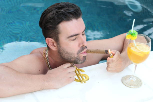 Man lighting cigar in luxurious swimming pool Man lighting cigar in luxurious swimming pool. pool at the crook stock pictures, royalty-free photos & images