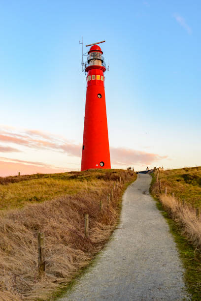 camino hacia el faro en las dunas en la isla de schiermonnikoog en el regio de waddensea durante la puesta del sol - lighthouse beacon north sea coastal feature fotografías e imágenes de stock