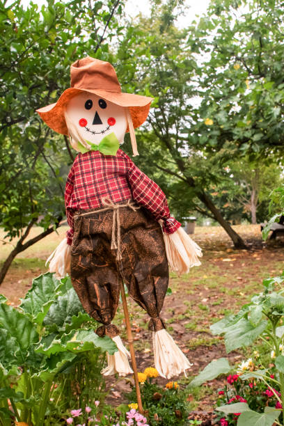 istock Cute scarecrow wearing hat stands in the garden. Selective focus. 1273854716