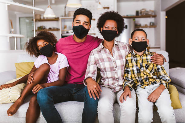 African American family wearing protective masks African American parents and cute small kids wearing protective masks at home. Stop the virus and epidemic diseases. 40 44 years photos stock pictures, royalty-free photos & images