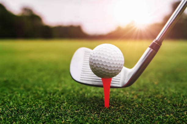 nahaufnahme golfschläger und golfball auf grünem rasen mit sonnenaufgangshintergrund - golf golf flag sunset flag stock-fotos und bilder
